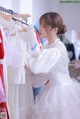 A woman in a white dress looking at a rack of dresses.