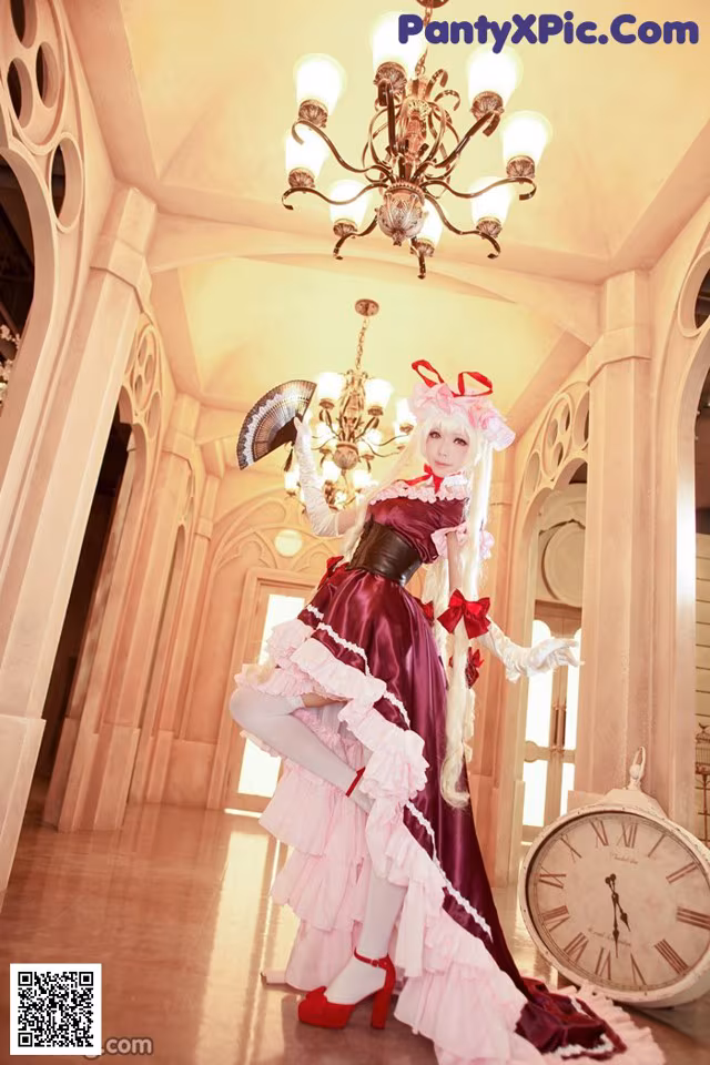 A woman in a pink and purple dress holding a fan.