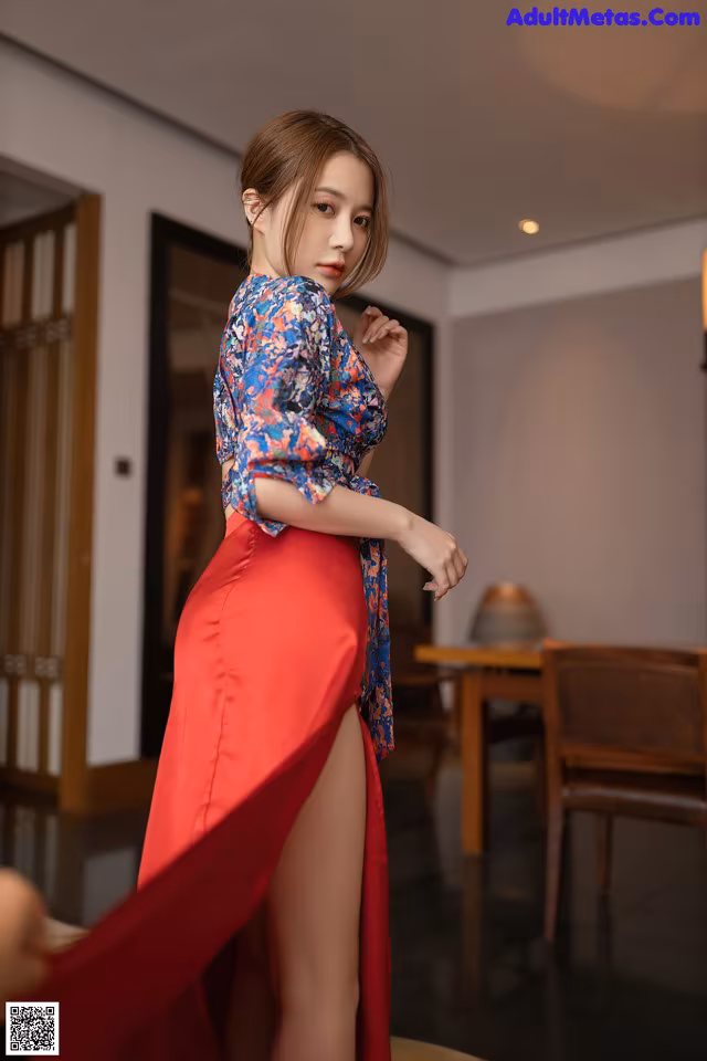 A woman in a red skirt is posing for a picture.