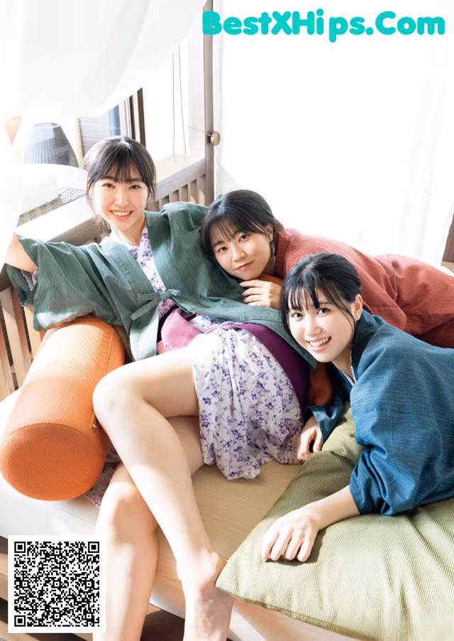 A group of three women sitting on top of a bed.