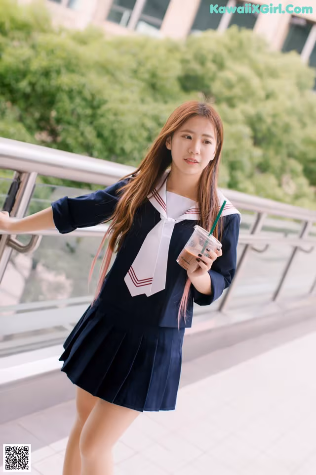 A woman in a school uniform holding a drink.