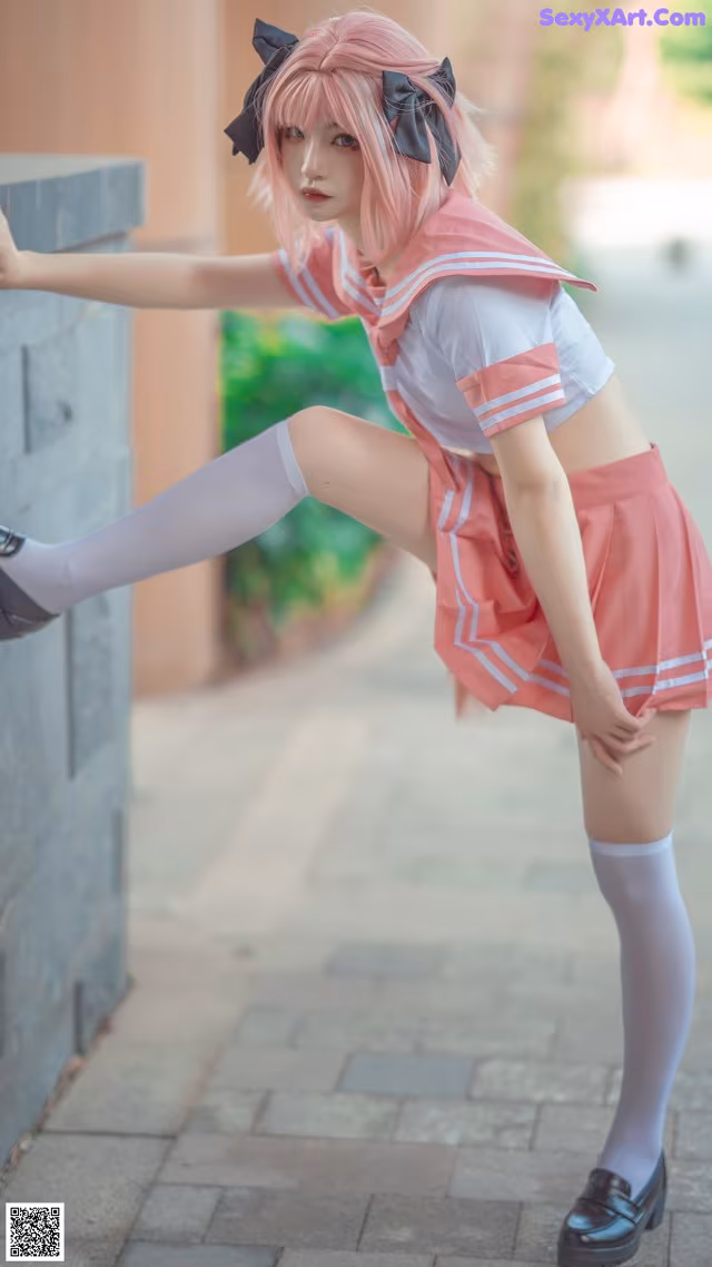 A woman in a pink and white uniform leaning against a wall.