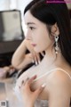 A woman in a white dress sitting in front of a mirror.