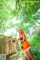 A woman in an orange dress holding a basket in the woods.