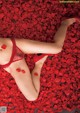 A woman laying on a bed of red rose petals.