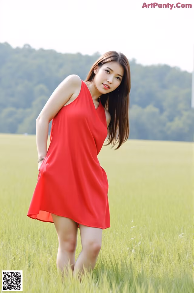 A woman in a red dress standing in a field.