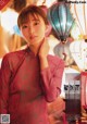 A woman in a pink dress standing in front of a bunch of lanterns.