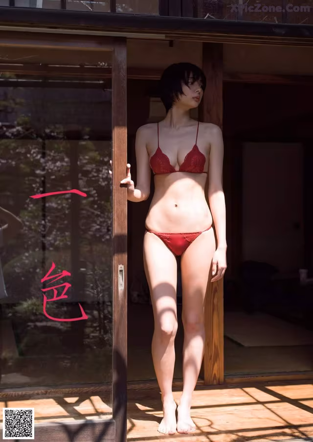A woman in a red bikini standing in front of a door.