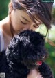 A young girl holding a black dog in her arms.