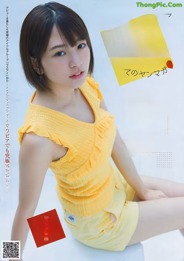 A woman in a yellow top and shorts sitting on the ground.