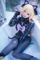 A woman in a black cat suit sitting in a bathtub.