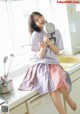 A young woman sitting on a kitchen counter holding a pan.