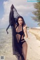 A woman in a black bikini standing on a beach.