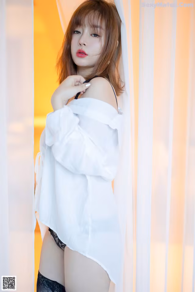 A woman in a white shirt and black stockings posing for a picture.
