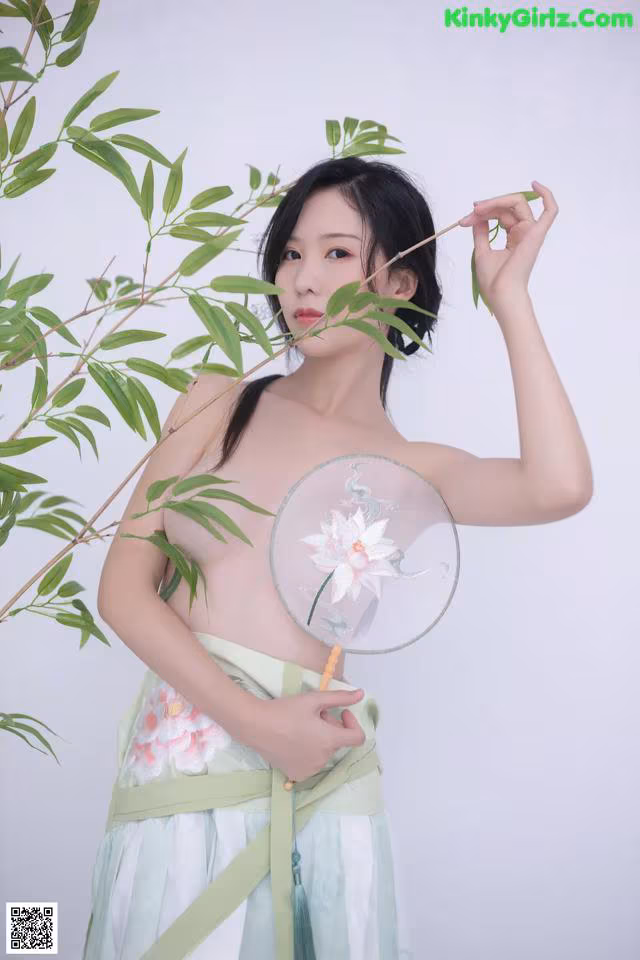 A woman in a green dress holding a fan.