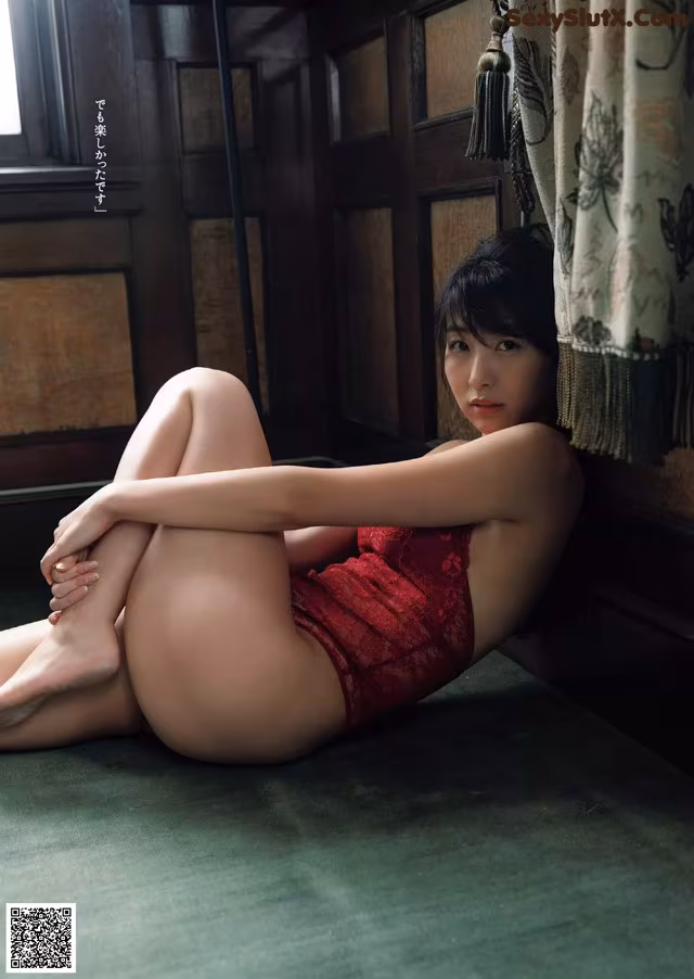 A woman in a red lingerie sitting on the floor.
