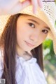 A young woman wearing a straw hat poses for a picture.