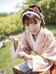 A woman in a pink kimono sitting on a wooden bench.