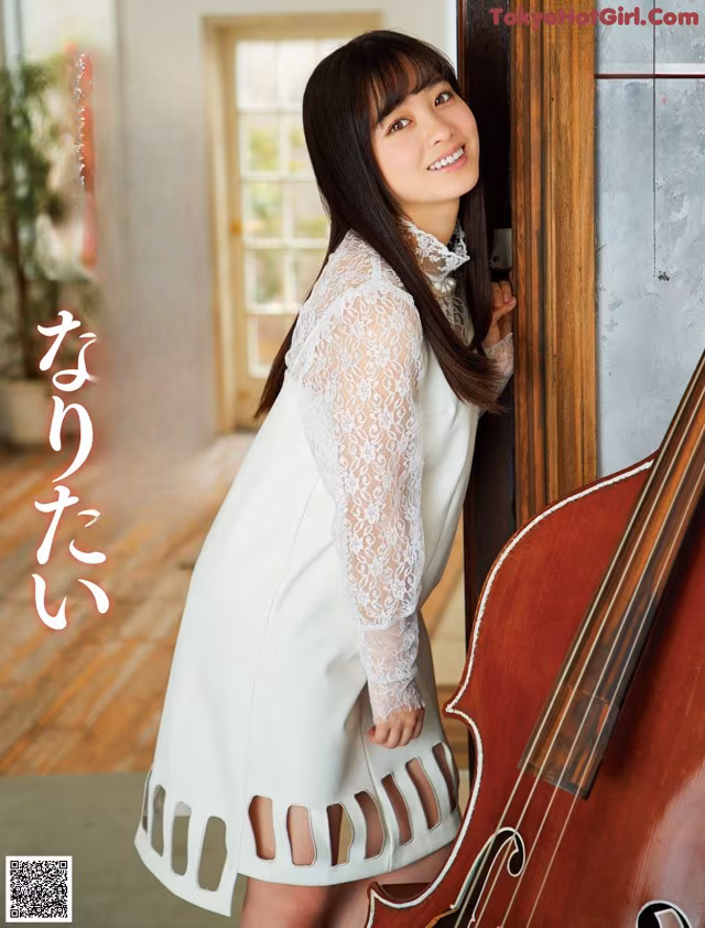 A woman in a white dress holding a cello.