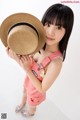 A young girl holding a straw hat over her head.