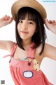 A young girl wearing a straw hat and overalls.