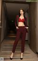 A woman in a red bra top and red pants standing in a hallway.