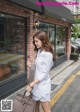 A woman walking down the street carrying a brown bag.