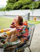 A woman sitting in a shopping cart talking on a cell phone.