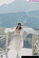 A woman in a white dress standing on a wooden bridge.