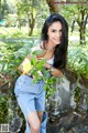 A woman in a white tank top and blue jeans posing for a picture.