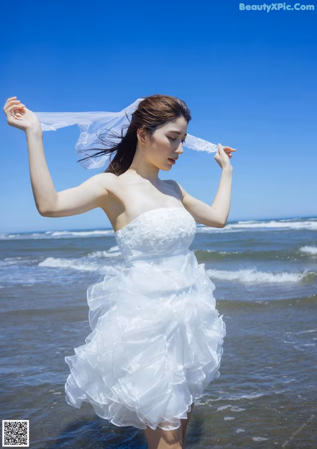 A woman in a wedding dress standing in the ocean.