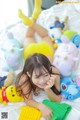 A woman laying on a bed surrounded by stuffed animals.